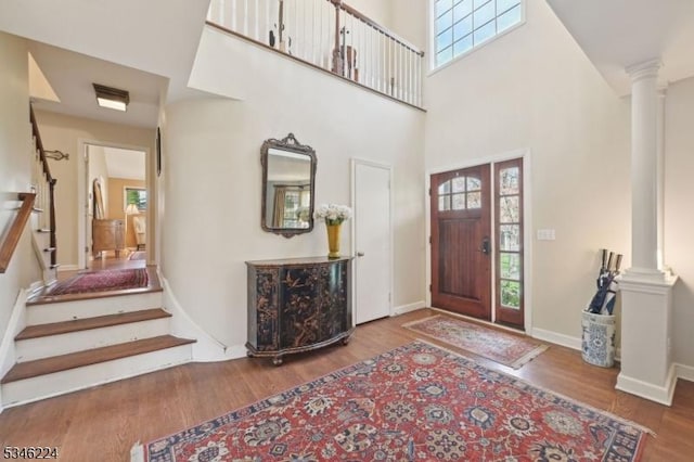 entrance foyer with ornate columns, wood finished floors, and stairs