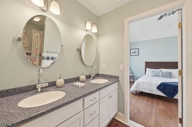 ensuite bathroom featuring double vanity, a sink, ensuite bathroom, and wood finished floors