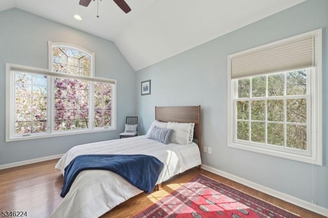 bedroom with wood finished floors, a ceiling fan, baseboards, and lofted ceiling