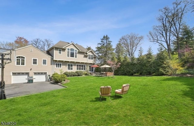 exterior space with an attached garage, a yard, and aphalt driveway