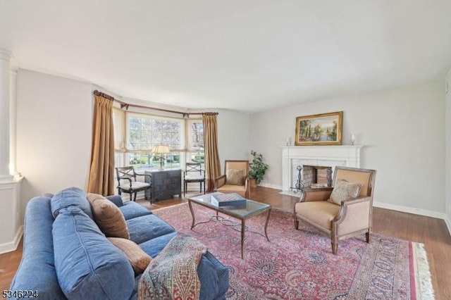 living room featuring baseboards, ornate columns, wood finished floors, and a premium fireplace