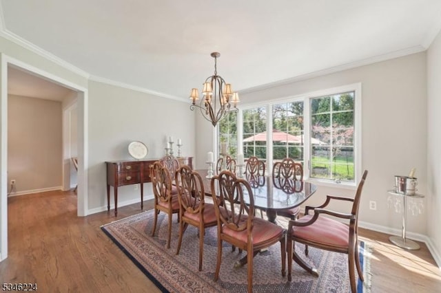 dining space with crown molding, baseboards, a notable chandelier, and wood finished floors