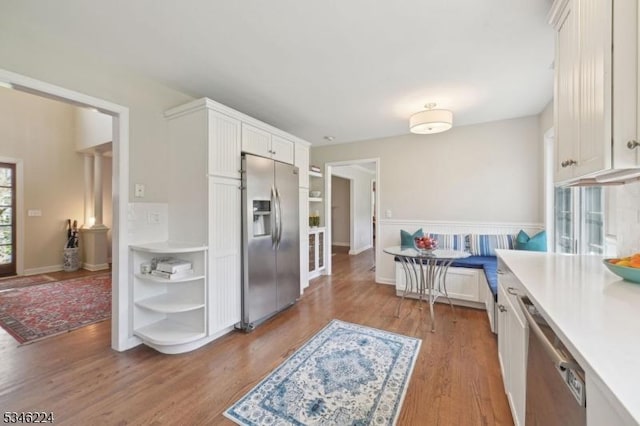 kitchen with white cabinets, open shelves, stainless steel appliances, and wood finished floors