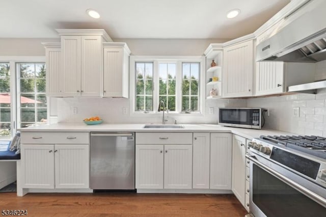 kitchen with wall chimney range hood, appliances with stainless steel finishes, recessed lighting, and a sink