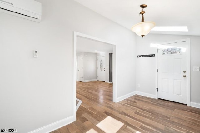 foyer with a wall mounted air conditioner, baseboards, and wood finished floors