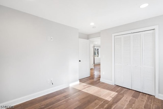 unfurnished bedroom featuring baseboards, wood finished floors, and recessed lighting
