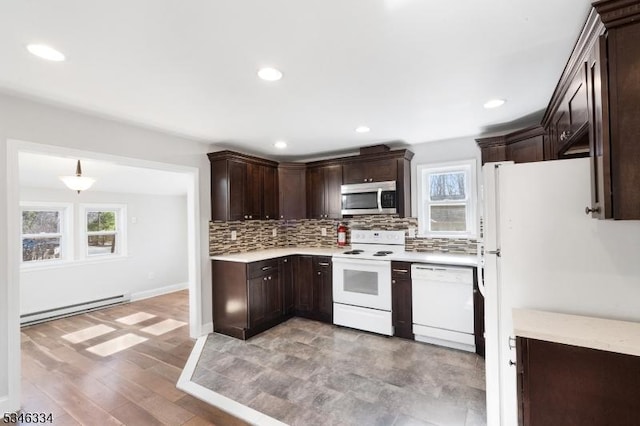 kitchen with light countertops, tasteful backsplash, baseboard heating, white appliances, and dark brown cabinets
