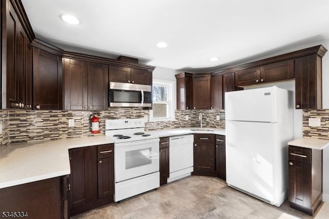 kitchen featuring light countertops, white appliances, dark brown cabinets, a sink, and backsplash