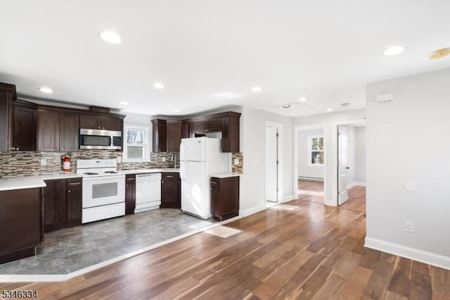 kitchen with dark brown cabinetry, plenty of natural light, and white appliances