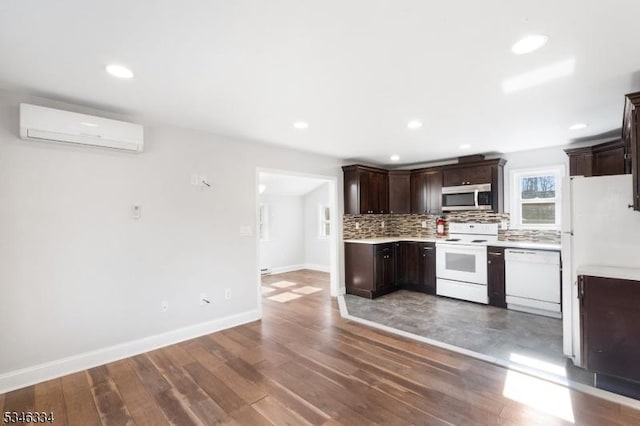 kitchen featuring backsplash, dark brown cabinetry, an AC wall unit, and white appliances