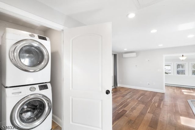 clothes washing area with recessed lighting, stacked washing maching and dryer, a wall mounted air conditioner, laundry area, and wood finished floors