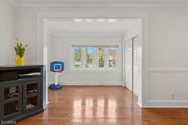 doorway to outside with wood finished floors, crown molding, and baseboards