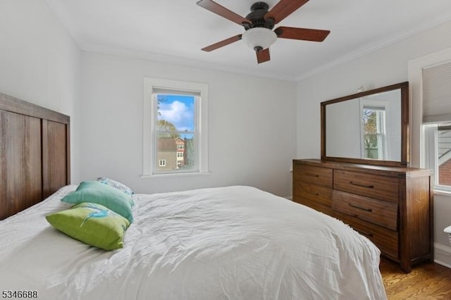 bedroom with ceiling fan, ornamental molding, and wood finished floors