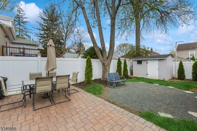 view of patio with a fenced backyard, an outbuilding, a storage shed, and outdoor dining area