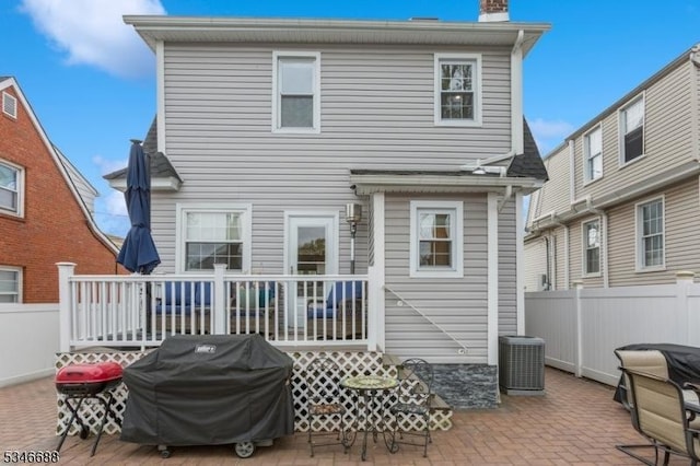 back of house featuring a chimney, fence, central air condition unit, a patio, and a deck