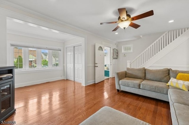 living area with a ceiling fan, wood finished floors, stairs, a wood stove, and recessed lighting