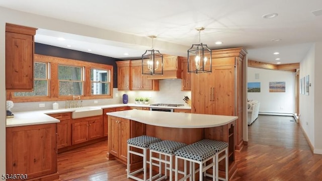 kitchen featuring a breakfast bar, a sink, dark wood finished floors, a center island, and recessed lighting