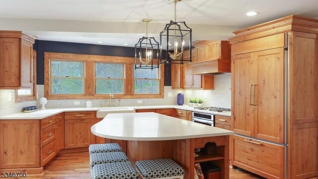 kitchen featuring light wood-type flooring, light countertops, a sink, a notable chandelier, and stainless steel appliances