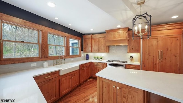 kitchen with stainless steel gas cooktop, wall oven, a sink, light wood finished floors, and recessed lighting