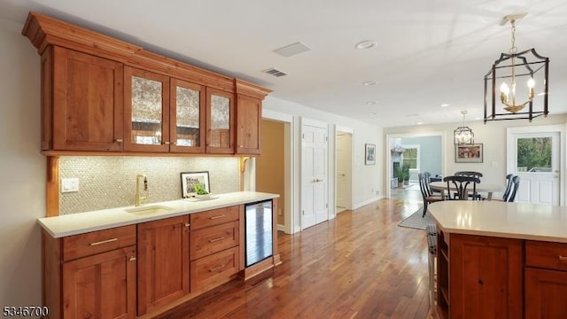kitchen with visible vents, beverage cooler, light countertops, tasteful backsplash, and hanging light fixtures