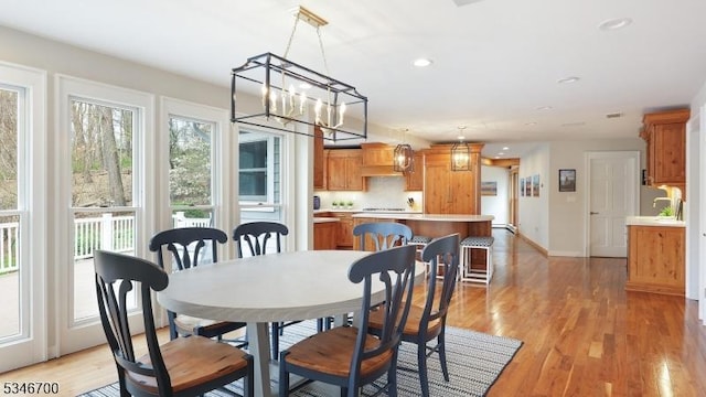 dining space with baseboards, light wood finished floors, recessed lighting, and a chandelier