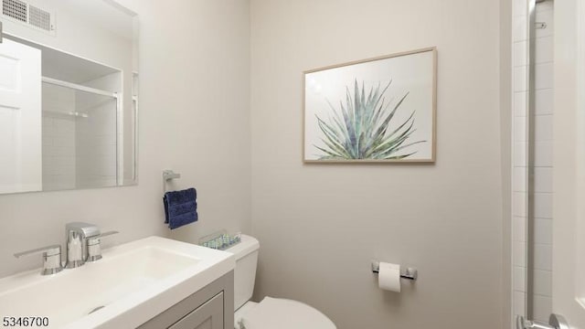 full bath with an enclosed shower, vanity, toilet, and visible vents