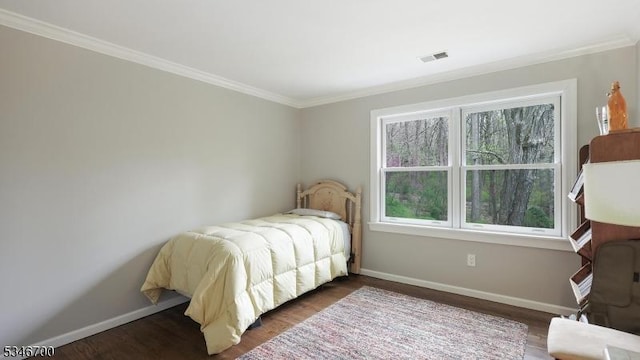 bedroom featuring baseboards, ornamental molding, wood finished floors, and visible vents