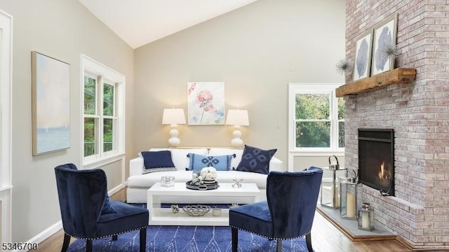 sitting room featuring a fireplace, wood finished floors, a wealth of natural light, and high vaulted ceiling
