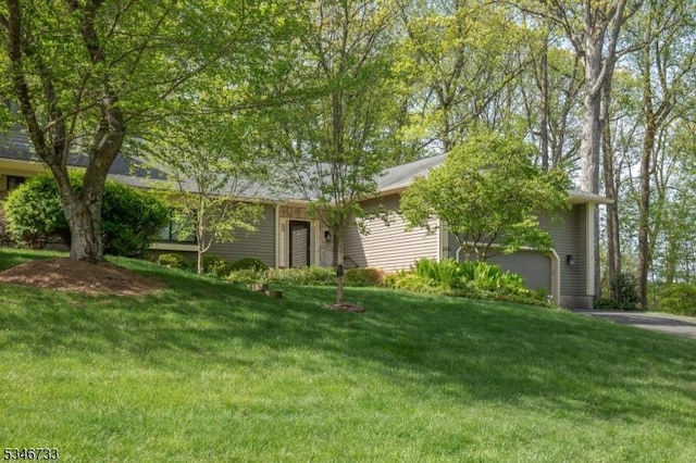 ranch-style house with an attached garage, driveway, and a front lawn