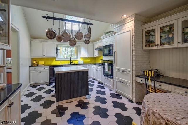 kitchen featuring a sink, lofted ceiling, black appliances, and dark countertops