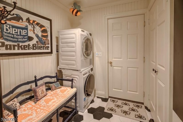 laundry area featuring tile patterned flooring, ornamental molding, wood walls, and stacked washer / dryer