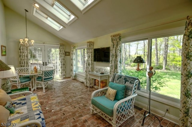 sunroom / solarium with baseboards, lofted ceiling with skylight, brick floor, a chandelier, and french doors