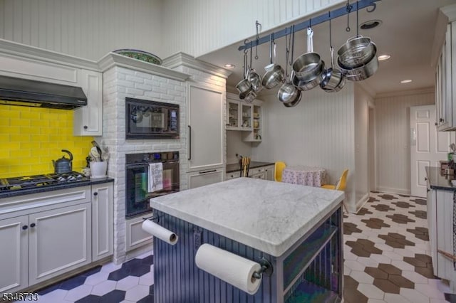 kitchen with a center island, light floors, black appliances, and tasteful backsplash