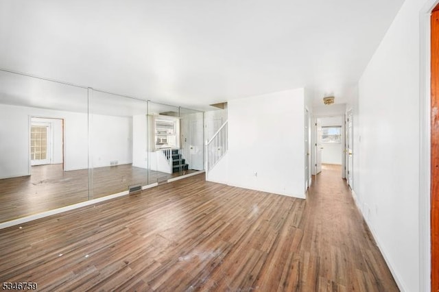 unfurnished living room featuring stairway and wood finished floors