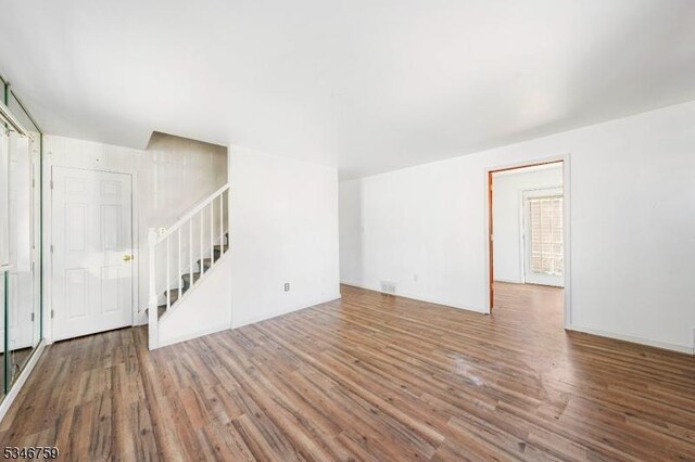 unfurnished living room with stairway and wood finished floors