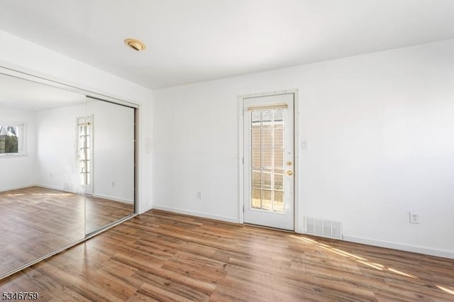 empty room featuring baseboards, visible vents, and wood finished floors