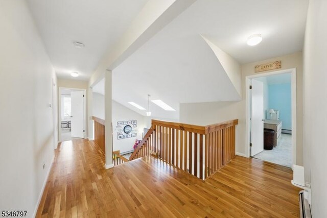 100 Toner Rd, Boonton Town, NJ 07005 - corridor featuring an upstairs landing, vaulted ceiling with skylight, a baseboard heating unit, and wood finished floors