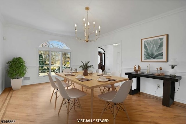 dining space with a notable chandelier, ornamental molding, and light wood-type flooring