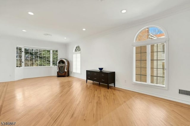 living room with crown molding, light wood-type flooring, baseboards, visible vents, and recessed lighting