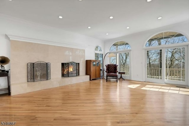 living area with recessed lighting, ornamental molding, a fireplace, and wood finished floors