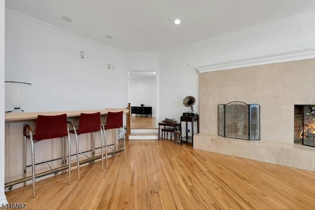 interior space with ornamental molding, light wood-style flooring, and a tiled fireplace