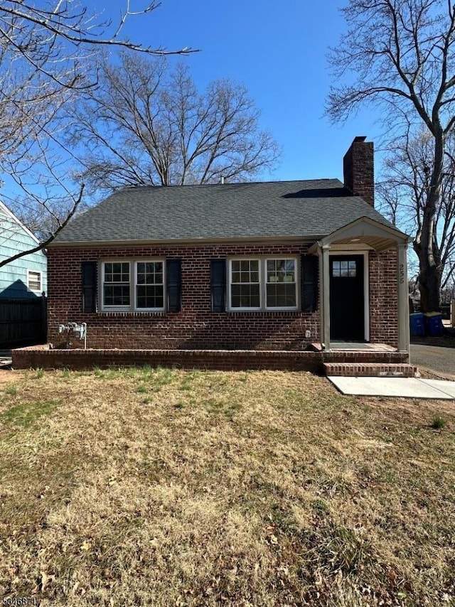 single story home with brick siding, a shingled roof, and a chimney