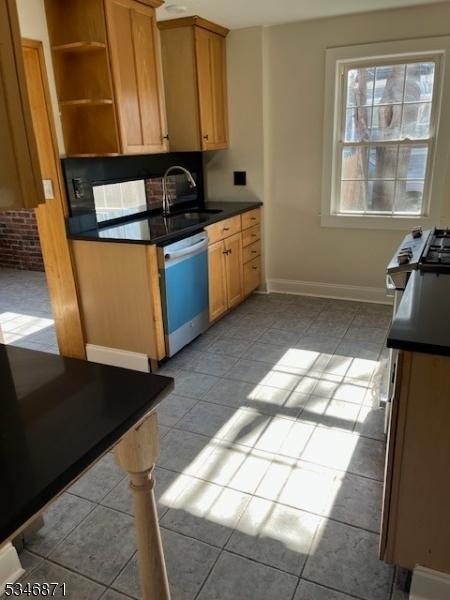 kitchen with a sink, dark countertops, tile patterned flooring, and dishwasher
