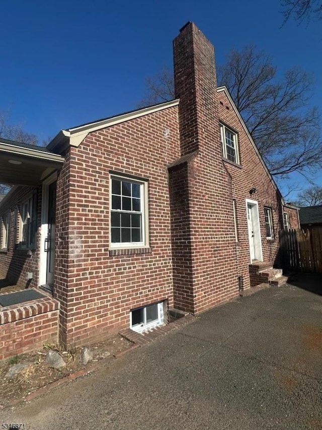 view of side of property featuring a chimney and brick siding
