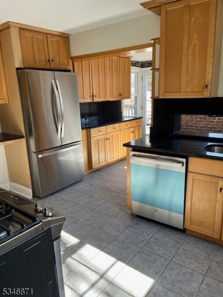 kitchen with backsplash, dark countertops, light tile patterned flooring, and stainless steel appliances