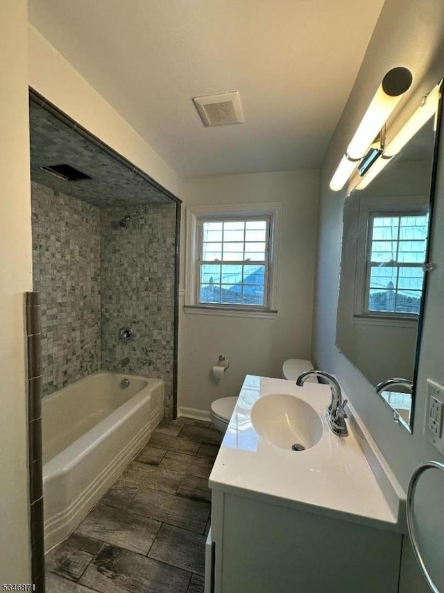 full bathroom featuring visible vents, toilet, wood finish floors, vanity, and shower / bath combination