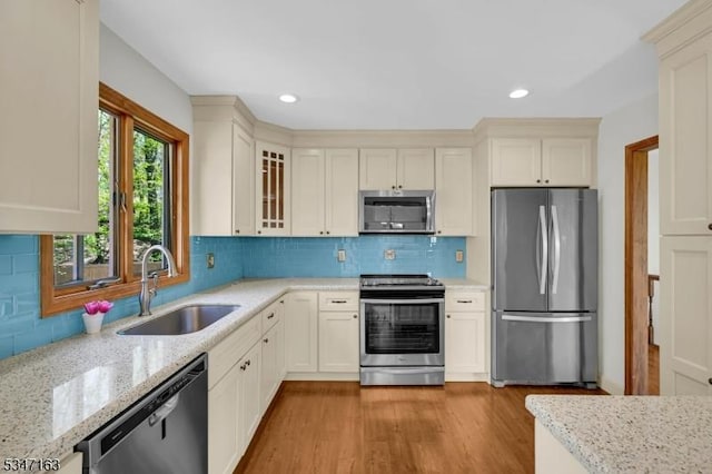 kitchen featuring light stone counters, a sink, recessed lighting, and stainless steel appliances