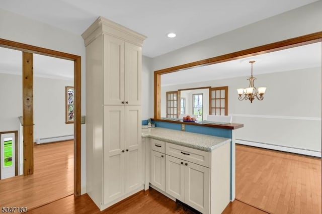 kitchen featuring a peninsula, a baseboard heating unit, plenty of natural light, and wood finished floors