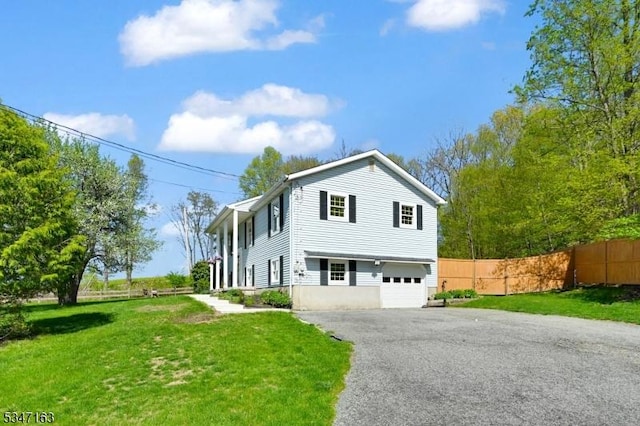 view of front facade featuring fence, an attached garage, driveway, and a front lawn