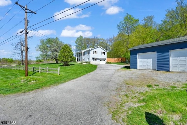 exterior space featuring fence, a detached garage, and a front lawn